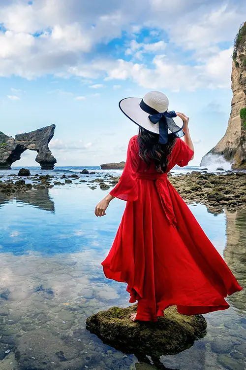 a lady with hat and blue dress in beach 