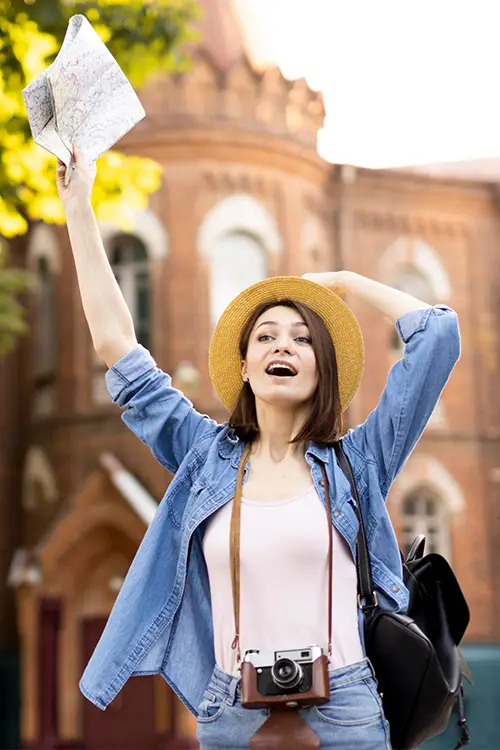 an excited traveller lady wearing hat and holding map in one hand