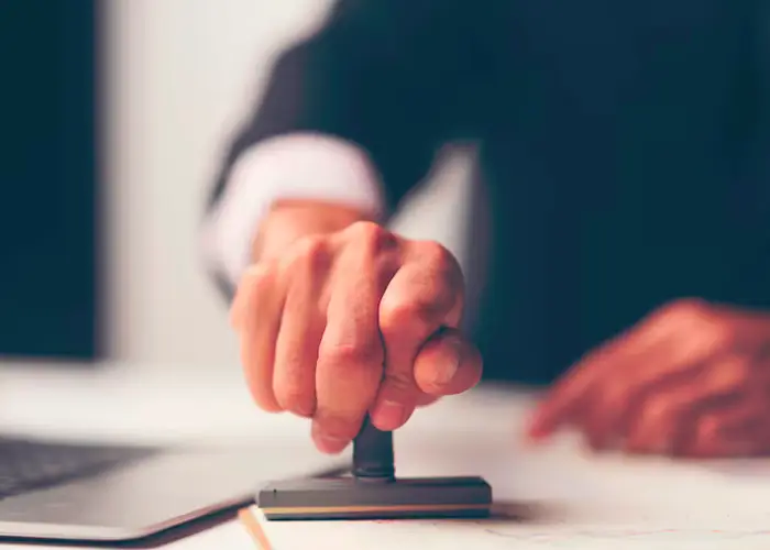 A person in a suit using a stamp on a document.