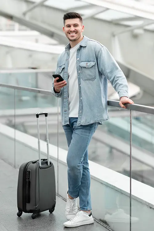 handsome young traveller with trolley bag olds amobile in the airport