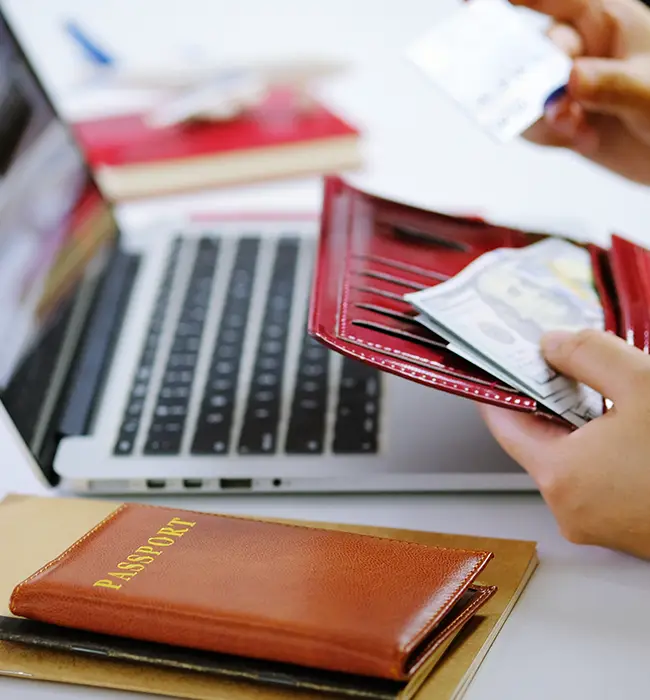 passport and foreign currency in the walle; laptop in background